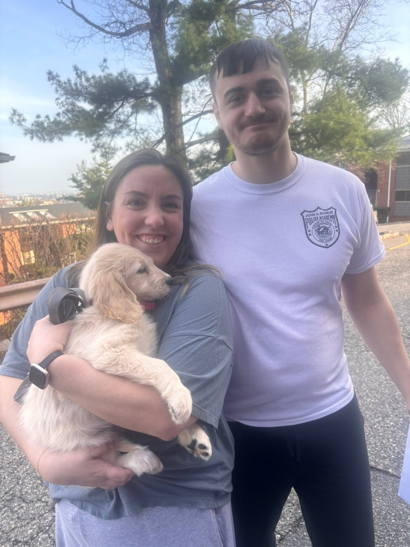 Smiling couple holding their new golden retriever puppy at the moment of delivery